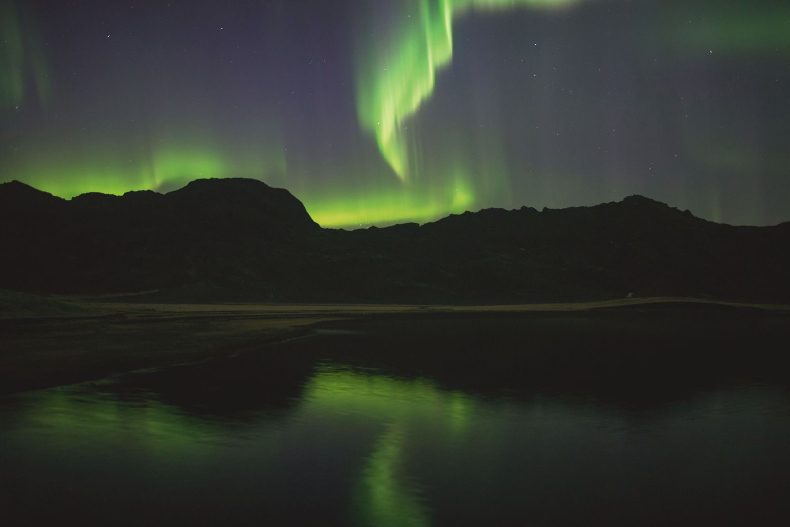 Northern lights over a lake and mountains in Iceland